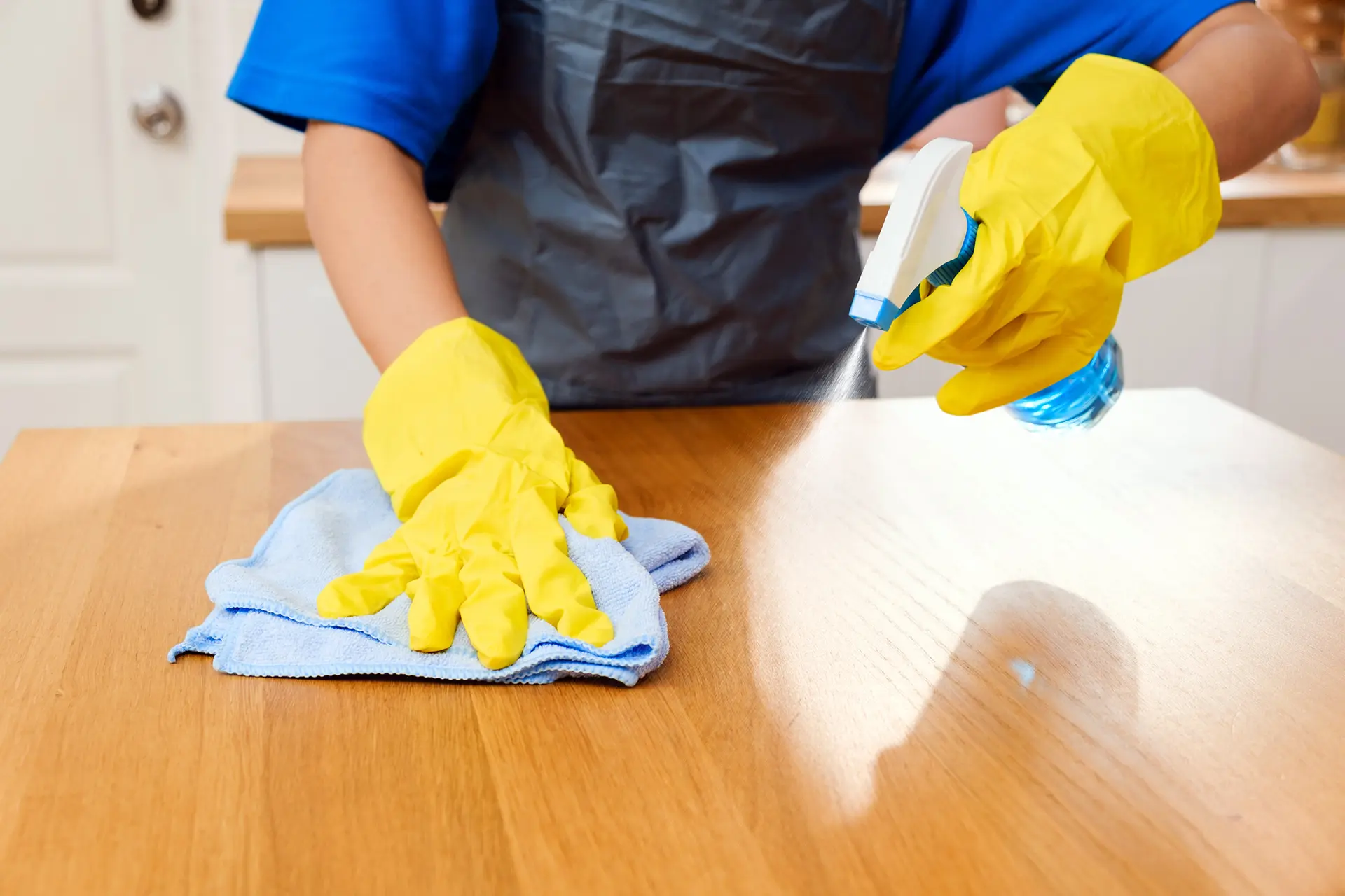 House cleaning service Sedona AZ – professional disinfecting and wiping kitchen table with spray cleaner