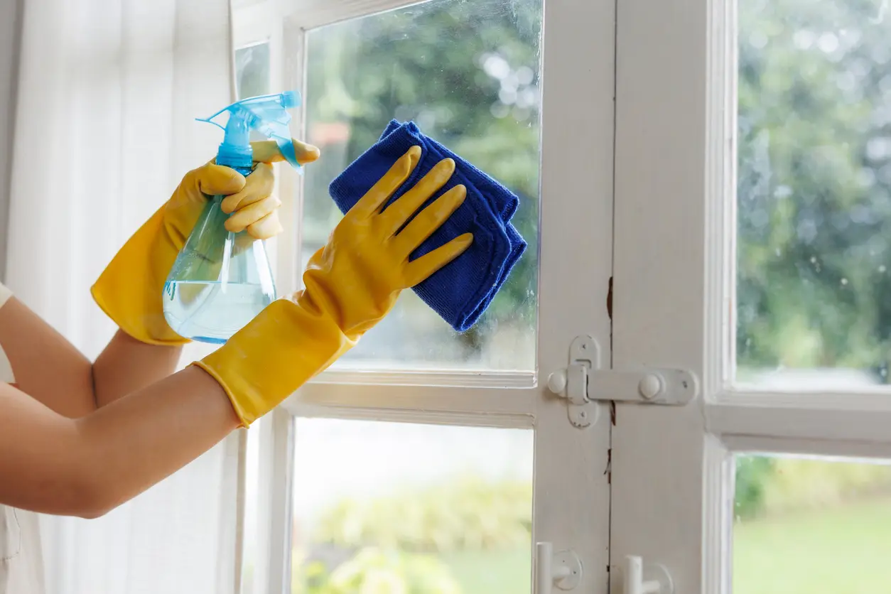 Cleaner wiping interior window glass with a microfiber cloth during a home cleaning in Sedona AZ